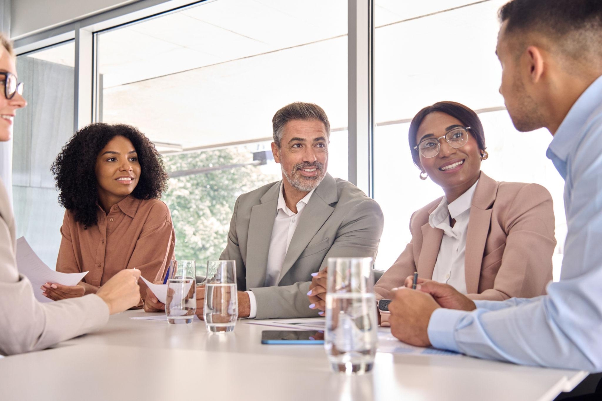 Participative leadership style demonstrated by diverse professionals engaged in collaborative discussion around a conference table, sharing ideas and listening to each other's perspectives.