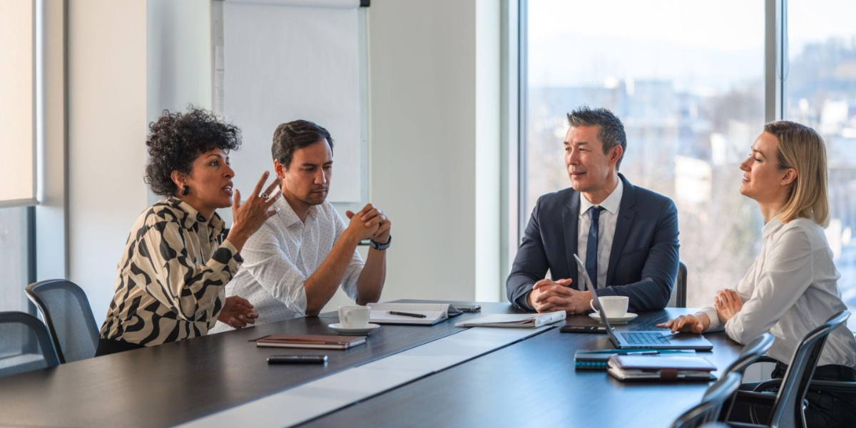 Participative leadership style illustrated by diverse professionals engaged in open dialogue and active listening during a high-rise office meeting with city views.